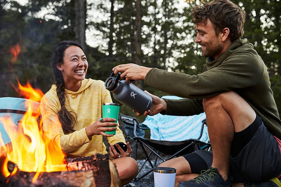 Eine Frau und ein Mann lachend am Lagerfeuer