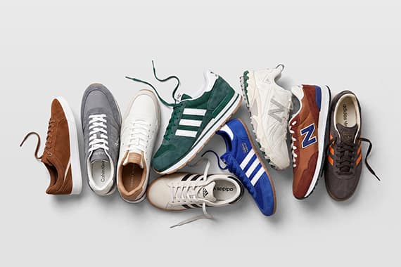 Mehrere bunte Sneaker verschiedener Marken liegen locker nebeneinander, einige mit offenen Schnürsenkeln
