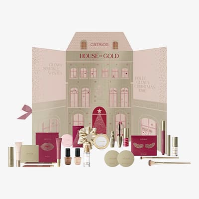 House of Gold Adventskalender mit geöffneter Hauskulisse und davor aufgereihten Make-up-Produkten in Rosa- und Goldtönen