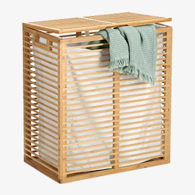 Wäschekorb mit Lattenstruktur und grünem Handtuch darüber drapiert