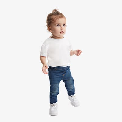 Kind in weißem T-Shirt und blauer Jeans steht aufrecht, trägt weiße Schuhe