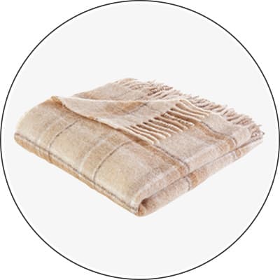 Beige karierte Decke mit Fransen, zusammengefaltet auf weißem Hintergrund.