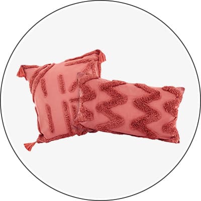 Zwei rosa Kissen mit verschiedenen Mustern und Quasten an den Ecken, eines mit Streifen und das andere mit Zickzacklinien.