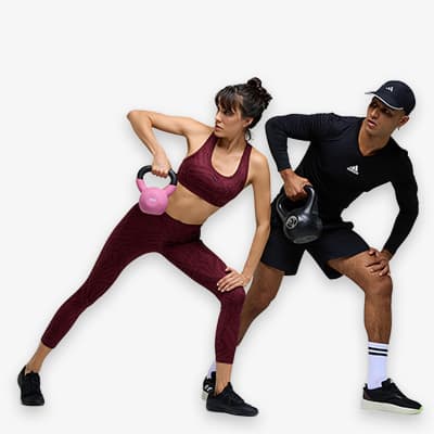 Frau in burgunderrotem Sportoutfit und Mann in schwarzer Sportkleidung trainieren mit Kettlebells