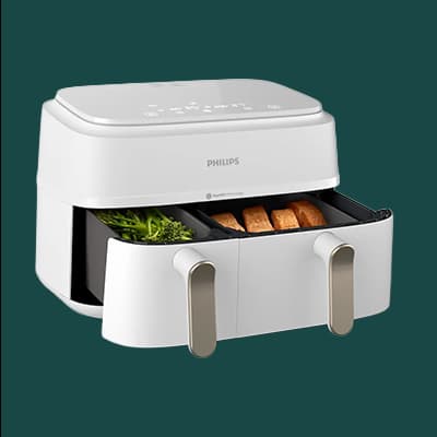 Philips Airfryer mit geöffneten Fächern, gefüllt mit Kräutern und Brotstücken, auf grünem Hintergrund