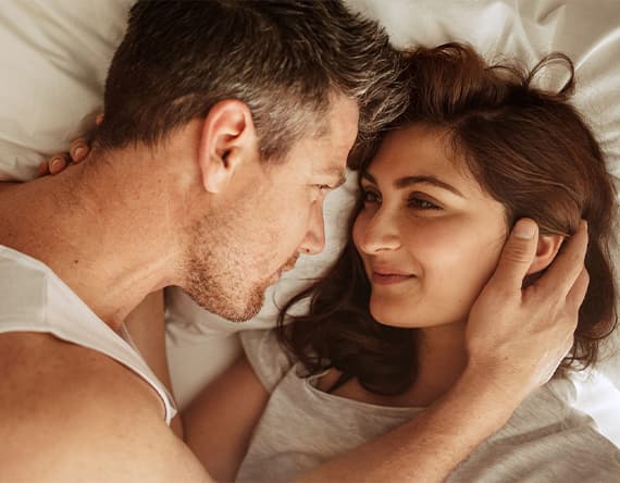 Mann und Frau liegen eng umschlungen auf einem Bett, ihre Gesichter sind verschwommen.