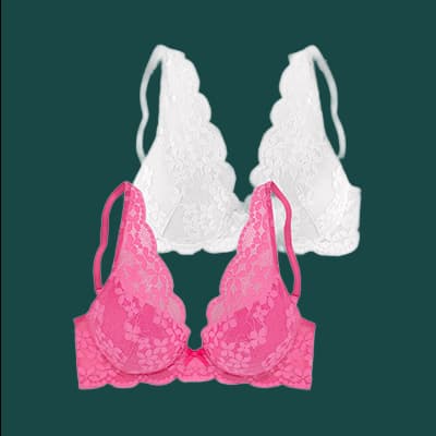 Zwei Spitzen-BHs, einer in Weiß und einer in Pink, vor dunklem Hintergrund