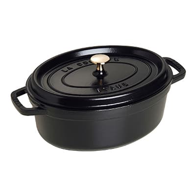 Schwarzer ovaler Kochtopf mit zwei Griffen und einem Deckel mit Knopf, Aufschrift "La Cocotte Staub" auf dem Deckel.