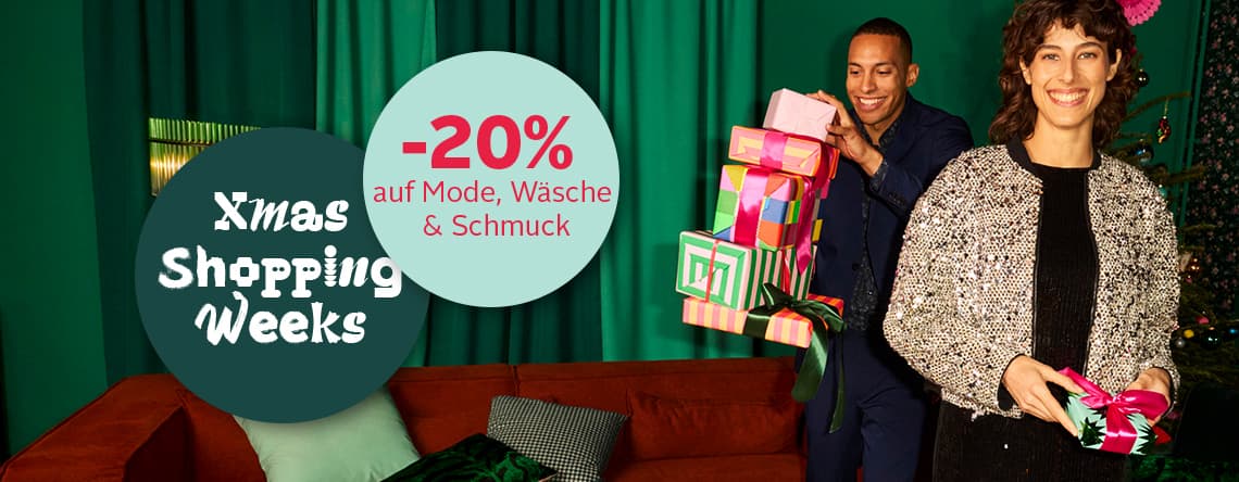-20 % auf Mode, Wäsche & Schmuck – Frau mit silberner Jacke und Mann in blauem Anzug tragen Geschenke vor grünem Hintergrund