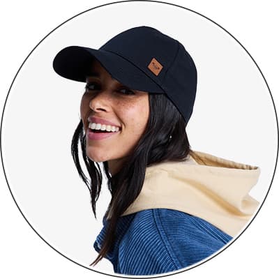 Frau mit schwarzer Baseballkappe und blau-beigem Hoodie von hinten.