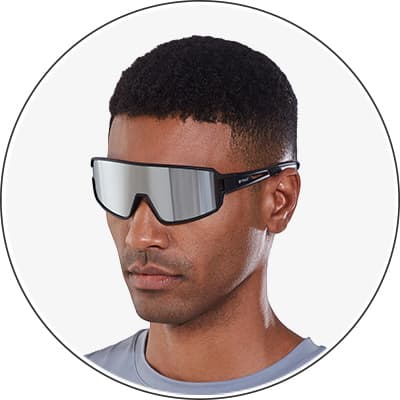 Mann mit Kurzhaarschnitt und Brille, Gesicht unscharf, trägt graues Oberteil.