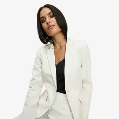 Frau trägt weißen Blazer und weiße Hose über schwarzem Oberteil