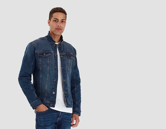 Person trägt blaue Jeansjacke und weiße T-Shirt mit blauer Jeans, Hand in Hosentasche.