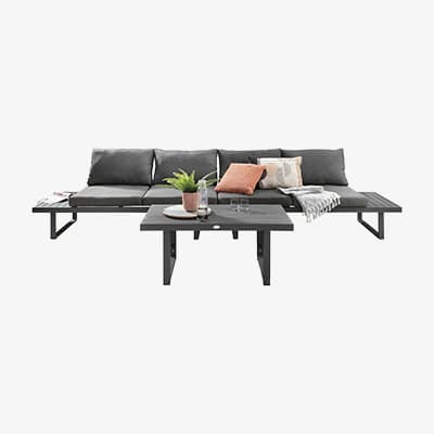 Graue Outdoor-Sofagarnitur mit Kissen und Tisch, darauf Pflanze und Getränke