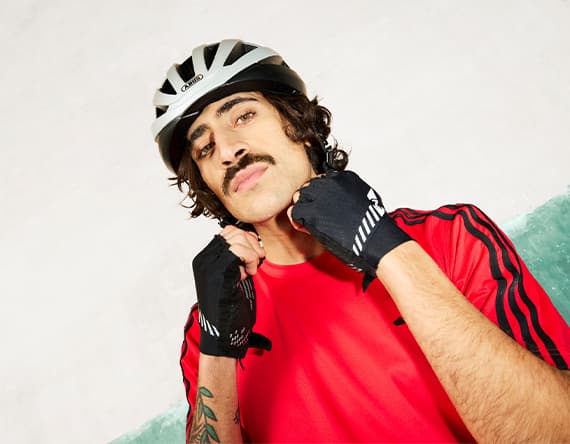 Person im roten Sportshirt mit Fahrradhelm und Fahrradhandschuhen hebt beide Fäuste vor die Brust