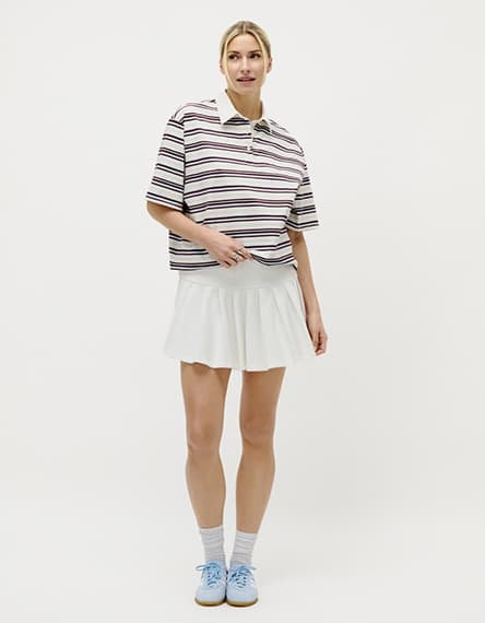 Frau trägt pink-gemusterte Bluse mit V-Ausschnitt und Jeansrock.