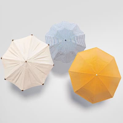 Drei geöffnete Sonnenschirme von oben: beige links, blau gestreift in der Mitte, gelb rechts auf hellem Hintergrund