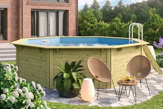Runder Aufstellpool im Garten vor einem Haus, daneben zwei Sessel, kleiner Tisch mit Getränken und Pflanzen