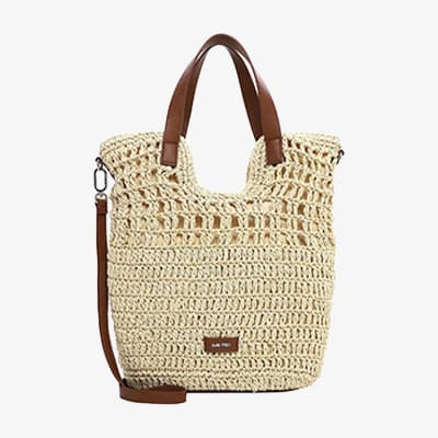 Beige geflochtene Handtasche mit braunen Henkeln und langem Schulterriemen vor weißem Hintergrund