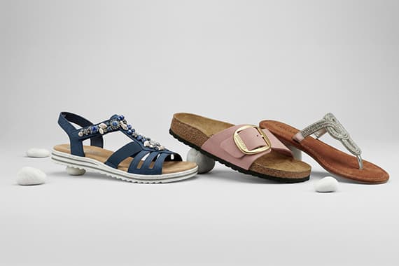 Drei unterschiedliche Damensandalen vor hellem Hintergrund, links Riemchensandale, mittig Pantolette, rechts Zehensandale