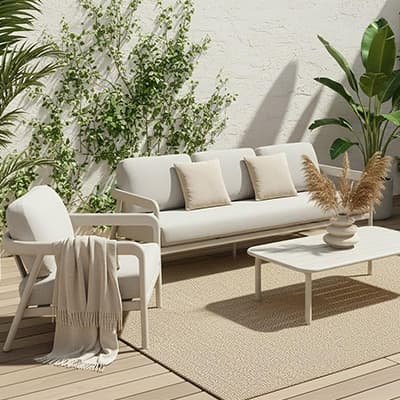 Moderne Terrassenmöbel: Sofa, Sessel und Tisch auf Holzdeck mit Pflanzen im Hintergrund.