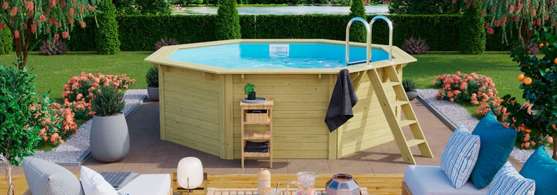 Achter-Pool mit Leiter in blühendem Garten, daneben Lounge-Ecke mit Kissen und kleinem Regal mit Handtüchern